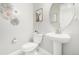 Stylish powder room with a pedestal sink, toilet, decorative mirror, and attractive wall decor at 8358 Howell St # B, Arvada, CO 80005