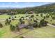Aerial view of a gray home on a large grassy lot, surrounded by dense trees and scenic views of the mountains in the background at 32399 Woodland Dr, Evergreen, CO 80439