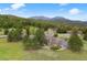 Aerial view of gray home on a lush green acreage, featuring mountain views surrounded by trees and greenery at 32399 Woodland Dr, Evergreen, CO 80439
