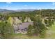 Aerial view of a gray house on sprawling green acreage, with trees and mountain views beyond at 32399 Woodland Dr, Evergreen, CO 80439