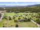 Overhead view of a gray home on a lush green acreage, highlighted by mature trees and mountain views at 32399 Woodland Dr, Evergreen, CO 80439