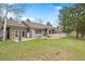 Expansive backyard view features a stone and siding home, a large grassy area, and mature trees providing a peaceful outdoor space at 32399 Woodland Dr, Evergreen, CO 80439