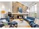 Bright living room boasts a stone fireplace, hardwood floors, and comfortable blue seating at 32399 Woodland Dr, Evergreen, CO 80439