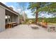 This large patio features a stone fireplace, bench seating, wooden picnic table and natural views from the backyard at 32399 Woodland Dr, Evergreen, CO 80439