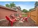An inviting backyard with a brick fire pit surrounded by red chairs, and a neatly stacked pile of firewood at 6011 Welch St, Arvada, CO 80004