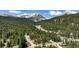 An aerial view of a cozy cabin nestled amongst a dense forest and trees with the mountains in the background at 29 Gregory Cir, Breckenridge, CO 80424