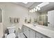 Bright bathroom featuring a white vanity, tile countertops, and a large mirror reflecting the shower at 2616 E Cherry Creek South Dr, Denver, CO 80209