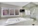 Bathroom with a large soaking tub, a mounted TV, and glass enclosed shower at 2616 E Cherry Creek South Dr, Denver, CO 80209