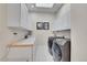 Laundry room with a skylight, washer, dryer, white storage cabinets, and counter space at 2616 E Cherry Creek South Dr, Denver, CO 80209