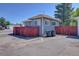 House side view with a red privacy fence and a paved driveway with trash cans at 5723 Zephyr St, Arvada, CO 80002