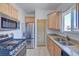 Modern kitchen with stainless steel appliances, light wood cabinets, and granite countertops at 5723 Zephyr St, Arvada, CO 80002