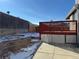 Backyard with a red wood deck, a concrete patio, a retaining wall, and a wooden fence at 6610 Monaco Way, Brighton, CO 80602