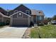 Charming home with a two-car garage, stone accents, manicured lawn, and inviting walkway at 6610 Monaco Way, Brighton, CO 80602