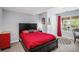 Bedroom featuring a black bed frame, red bedding, and access to an outdoor patio at 6039 S Ukraine Cir, Aurora, CO 80015