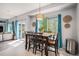 Bright dining room with stylish light fixture, dark wood table, and large windows with blue curtains at 6039 S Ukraine Cir, Aurora, CO 80015