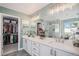 Modern main bathroom with dual sinks, a walk-in shower, and access to a walk-in closet at 6039 S Ukraine Cir, Aurora, CO 80015