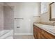 Bright bathroom with a combination tub and shower unit, tiled floors, and wood vanity at 2975 E Wesley Ave, Denver, CO 80210