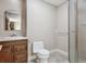 Well-lit bathroom featuring a vanity with wood cabinets, tiled floor, toilet, and glass shower at 2975 E Wesley Ave, Denver, CO 80210