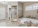 Bathroom featuring a soaking tub, glass-enclosed shower, and travertine tile at 2975 E Wesley Ave, Denver, CO 80210