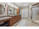 Large main bathroom with double vanity sinks, wood cabinets, and tiled floor at 2975 E Wesley Ave, Denver, CO 80210