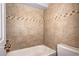Close up of a bathtub and toilet featuring neutral tile and decorative trim at 4634 S Fraser Ct # F, Aurora, CO 80015
