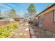 Paver pathway leading through a landscaped backyard, brick exterior, and covered pergola at 6101 E 3Rd Ave, Denver, CO 80220
