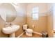 Stylish powder room with a pedestal sink, decorative mirror, beach-themed wall paper and tiled floor at 935 Green Gables Cir, Bennett, CO 80102