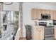 Bright kitchen with stainless steel appliances, light wood cabinets, a glass top dining table, and a view to the outside patio at 12961 Lafayette St # B, Thornton, CO 80241