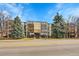 Exterior view of a well-maintained apartment building with mature trees and visible balconies on a sunny day at 6980 E Girard Ave # 204, Denver, CO 80224