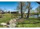 Picturesque backyard with a rocky stream, mature trees, and a pond, blending natural beauty with a peaceful setting at 16440 Old Denver Rd, Monument, CO 80132