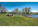 Expansive backyard with lush green grass, mature trees, a tranquil pond and a dock perfect for enjoying nature at 16440 Old Denver Rd, Monument, CO 80132