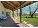 Relaxing covered porch featuring lounge seating and a picturesque view of the lush green lawn and pond at 16440 Old Denver Rd, Monument, CO 80132