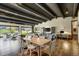 Bright open-concept living and dining room featuring hardwood floors, exposed beams, and large windows overlooking the property at 16440 Old Denver Rd, Monument, CO 80132