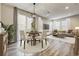 Stylish living and dining area with neutral tones, featuring a modern light fixture and a sliding glass door to the backyard at 3386 Valentia St, Denver, CO 80238