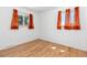 This bedroom features hardwood floors, bright natural light, and orange curtains at 1229 W 102Nd Ave, Northglenn, CO 80260