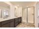 Bathroom with double sinks, dark cabinets, large mirrors, a glass-enclosed shower, and stylish tile flooring at 918 Congress Pl, Elizabeth, CO 80107