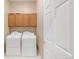 Practical laundry room with white appliances and wooden cabinets at 12790 Jackson St, Thornton, CO 80241