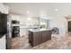Modern kitchen with white cabinets, center island, stainless appliances, and open to dining area at 39633 E 160Th Ave, Keenesburg, CO 80643