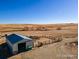 An aerial view of a metal outbuilding with blue roof and horse pen with arid landscape in the background at 39633 E 160Th Ave, Keenesburg, CO 80643