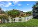 A well-manicured backyard featuring a white picket fence, lush lawn, and mature landscaping at 21885 Whirlaway Ave, Parker, CO 80138