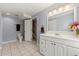 Bright bathroom featuring a large mirror, white vanity, tile floors, and view of stairway through door at 21885 Whirlaway Ave, Parker, CO 80138