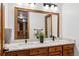 Bathroom featuring double sinks, a large mirror, a plant in the center, and wooden cabinetry at 9303 Dauntless Way, Conifer, CO 80433