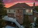 Exterior rear view of brick home featuring a deck, bay window, and scenic sunset backdrop at 9303 Dauntless Way, Conifer, CO 80433