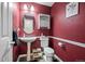 Bright half bathroom features a pedestal sink, oval mirror, and decorative red textured walls at 15800 E 121St Ave # 4K, Brighton, CO 80603