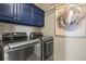 Laundry room with stainless steel front load washer and dryer and blue cabinets at 10828 Valleybrook Cir, Highlands Ranch, CO 80130