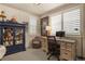 A well-lit room featuring a desk with a monitor, a display cabinet, and a cozy chair at 10828 Valleybrook Cir, Highlands Ranch, CO 80130