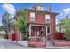 Charming two-story brick home featuring a covered porch and landscaped front yard on a sunny day at 2614 E 13Th Ave, Denver, CO 80206