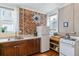 Functional kitchen with exposed brick wall, stainless steel sink, appliances, and wooden cabinets at 2614 E 13Th Ave, Denver, CO 80206