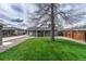 Expansive backyard featuring a covered patio, lush grass, and mature trees, ideal for outdoor activities at 5477 E Asbury Ave, Denver, CO 80222