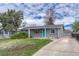 Well-maintained single-story home with grey brick, mature trees, blue door, and driveway at 5477 E Asbury Ave, Denver, CO 80222